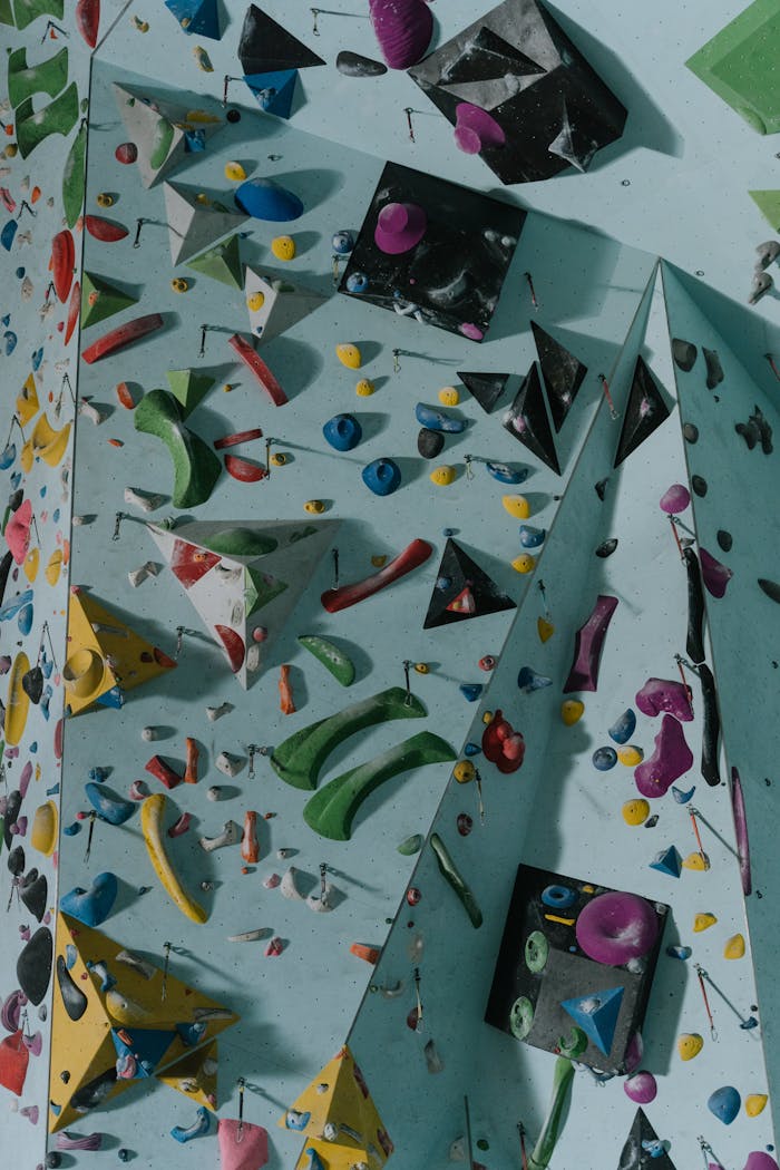 Dynamic indoor climbing wall with colorful holds and geometric shapes, ideal for bouldering enthusiasts.